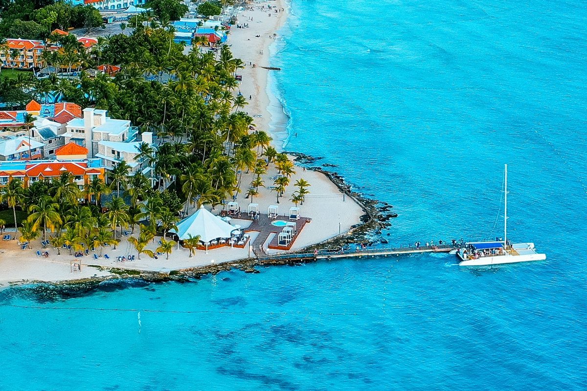 Vista aérea de una playa caribeña con hoteles entre palmeras y mar turquesa en República Dominicana